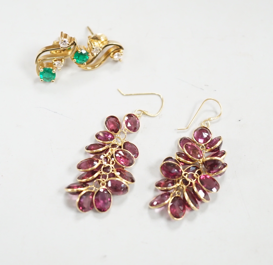 A modern pair of yellow metal, emerald and diamond set three stone ear studs, 14mm and a modern pair of yellow metal and garnet cluster set drop earrings, gross weight 8.3 grams.
